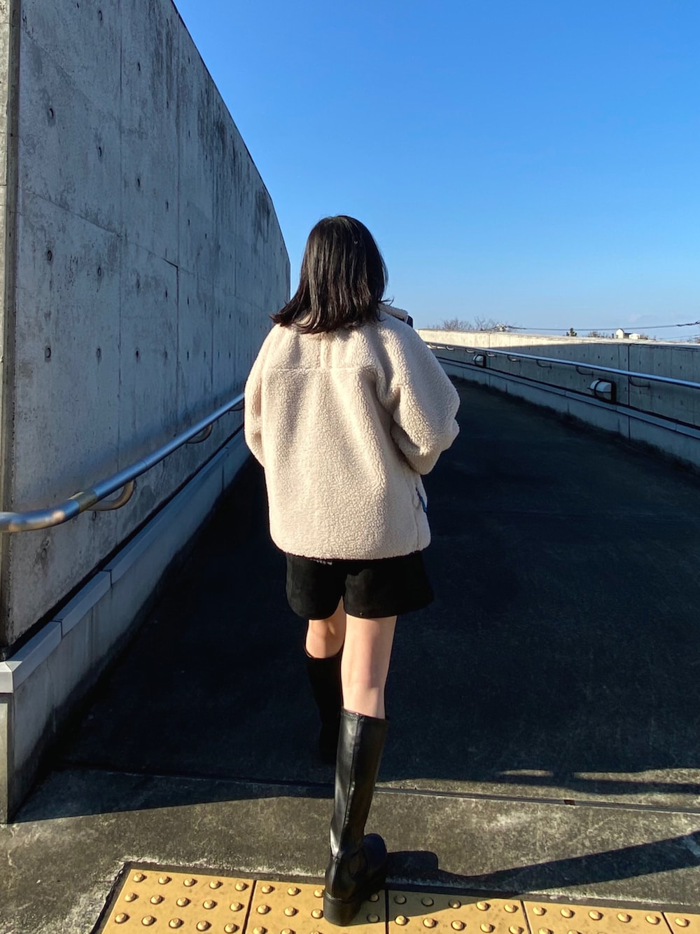 ホワイト系のブルゾン、ベージュ系のショルダーバッグ、グレー系のニット/セーターを着用したレディースの冬コーディネートの2枚目の写真