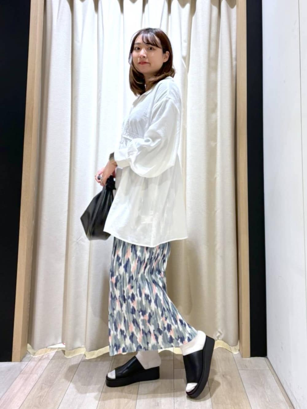 ブラック系のショルダーバッグ、ホワイト系のスカート、ブラック系のサンダルを着用したレディースの夏コーディネートの3枚目の写真