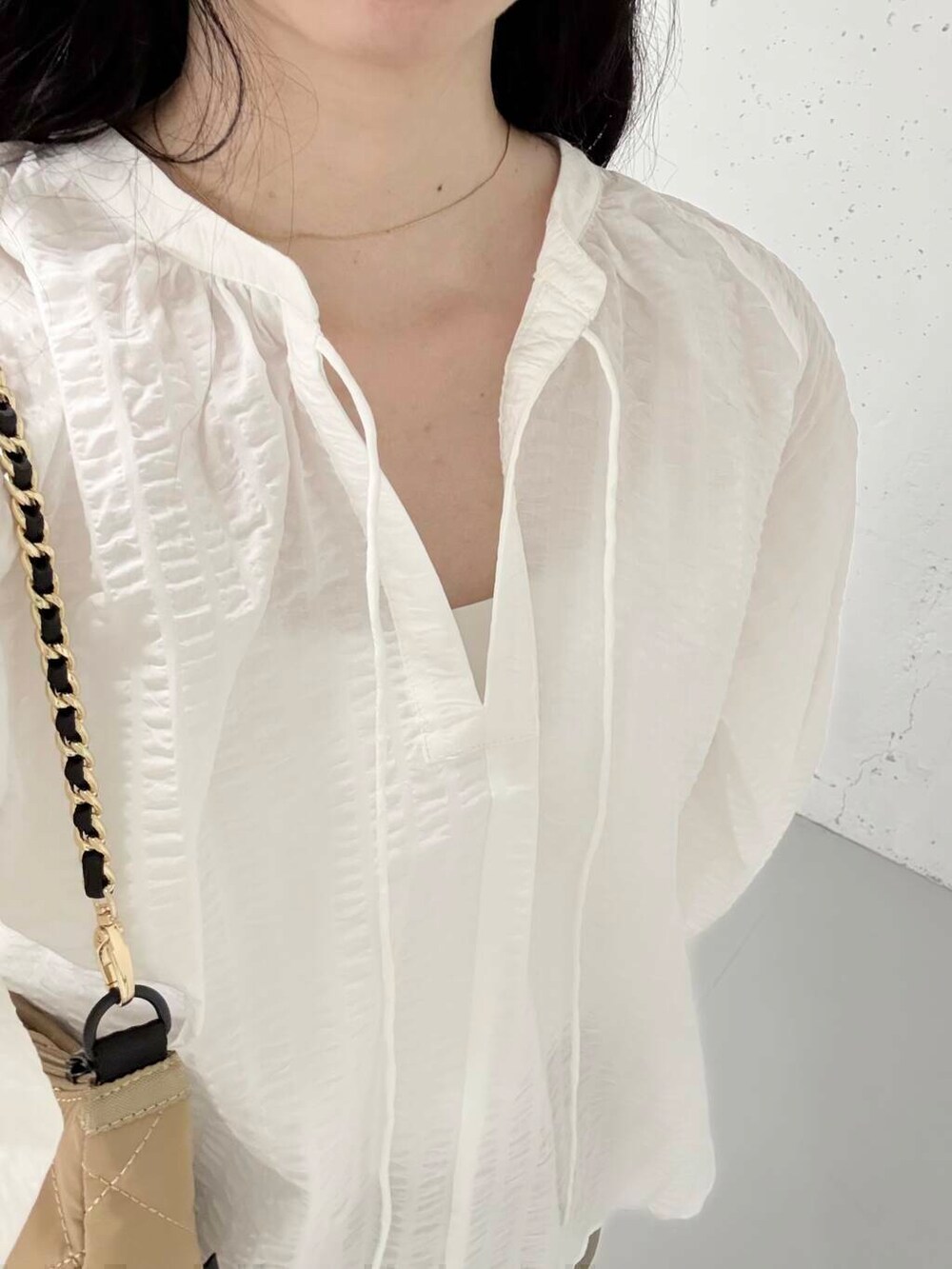 ブラウン系のその他パンツ、ベージュ系のハンドバッグ、ホワイト系のシャツ/ブラウスを着用したレディースの夏コーディネートの2枚目の写真