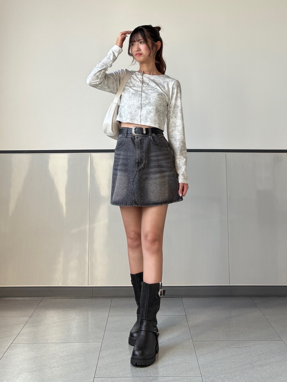 ホワイト系のTシャツ/カットソー、グレー系のデニムスカート、ブラック系のブーツを着用したレディースの秋コーディネートの3枚目の写真