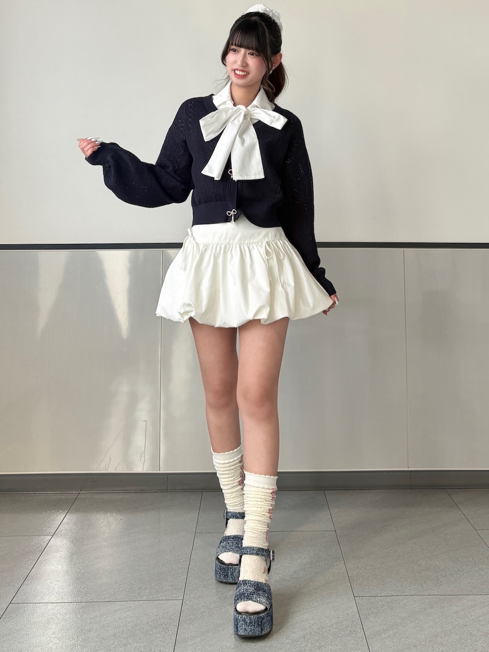 ブルー系のカーディガン/ボレロ、ホワイト系のスカート、ホワイト系のボストンバッグを着用したレディースの春コーディネートの2枚目の写真