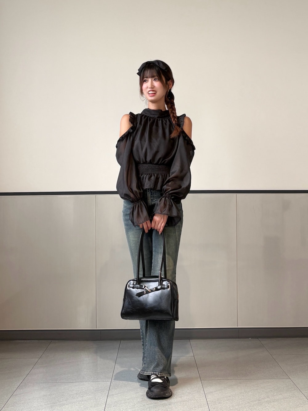 ブラック系のシャツ/ブラウス、ブラック系のハンドバッグ、ブルー系のデニムパンツを着用したレディースの秋コーディネートの3枚目の写真