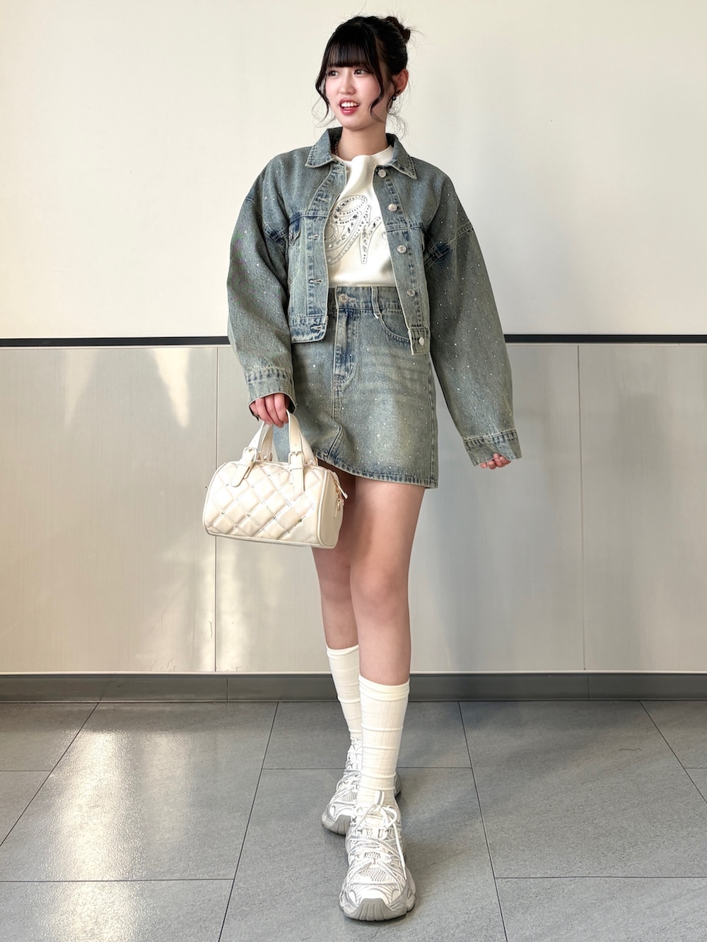 ブルー系のデニムジャケット、ブルー系のスカート、ホワイト系のボストンバッグを着用したレディースの春コーディネートの2枚目の写真