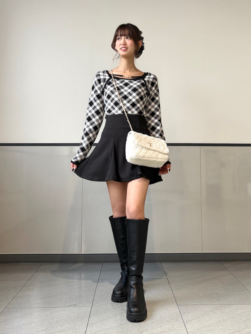 ブラック系のニット/セーター、ブラック系のスカート、ブラック系のブーツを着用したレディースの秋コーディネートの2枚目の写真