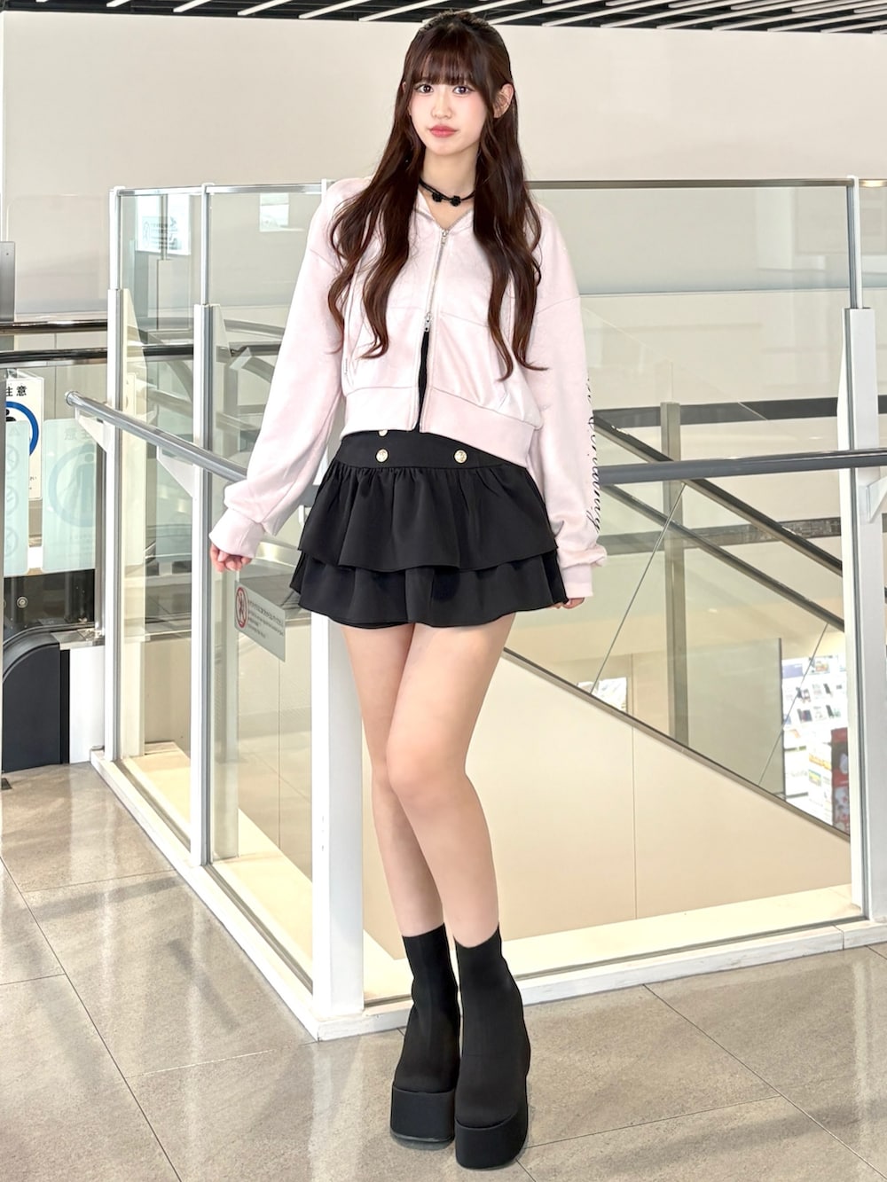 ピンク系のパーカー、ブラック系のスカート、ブラック系のブーツを着用したレディースの秋コーディネートの3枚目の写真