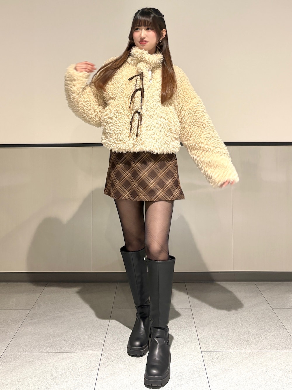 ベージュ系のブルゾン、ブラウン系のスカート、ブラック系のブーツを着用したレディースの冬コーディネートの2枚目の写真