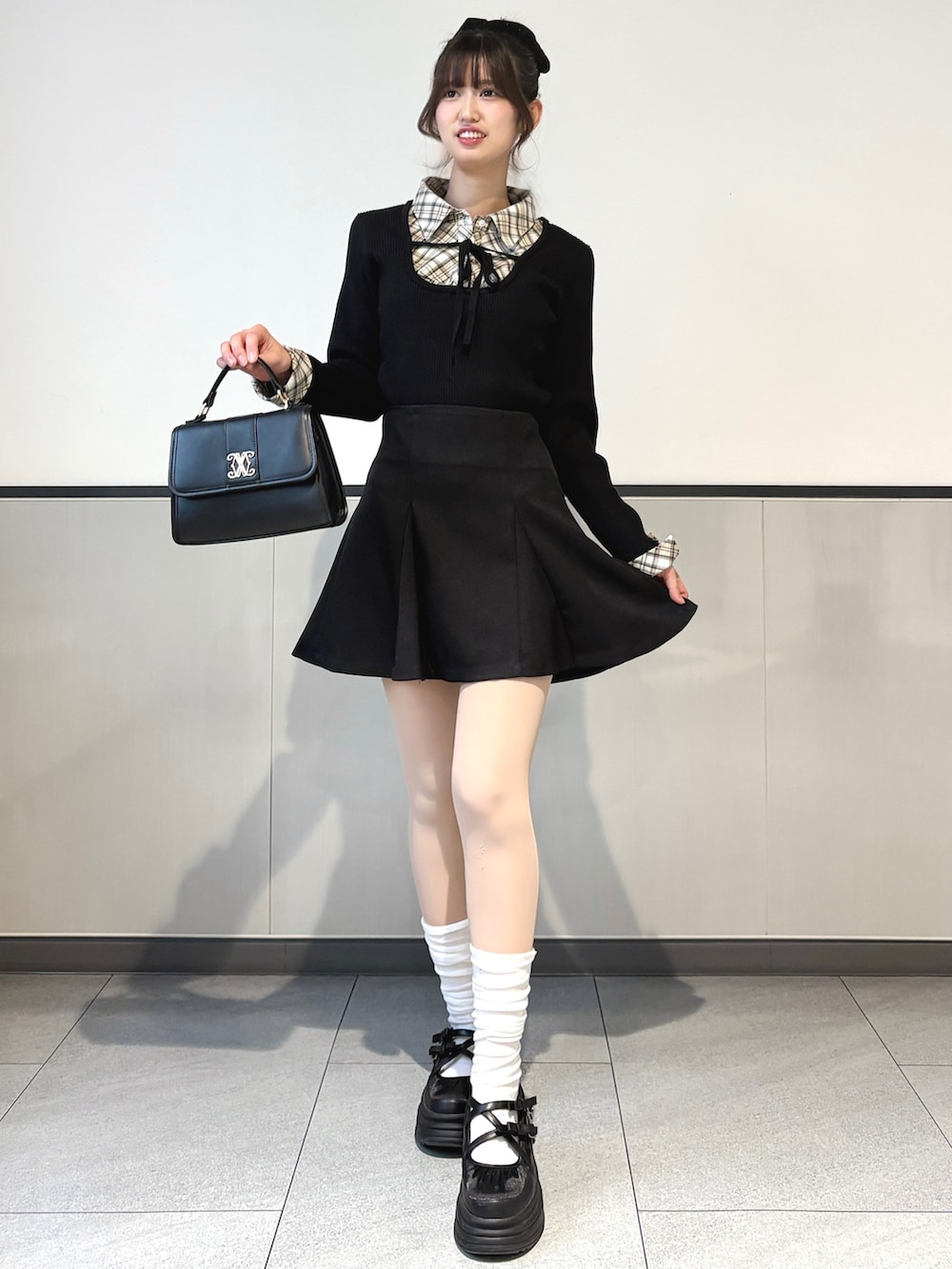 ブラック系のニット/セーター、ブラック系のスカート、ブラック系のハンドバッグを着用したレディースの冬コーディネートの2枚目の写真