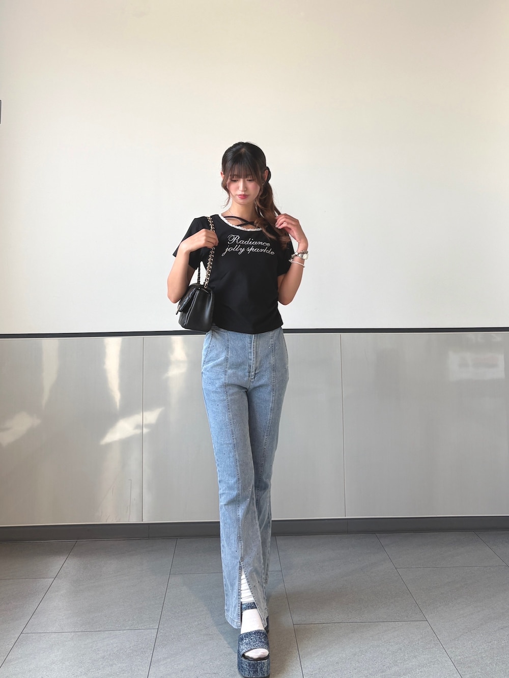 ブラック系のTシャツ/カットソー、ブルー系のデニムパンツ、ブラック系のショルダーバッグを着用したレディースの秋コーディネートの2枚目の写真