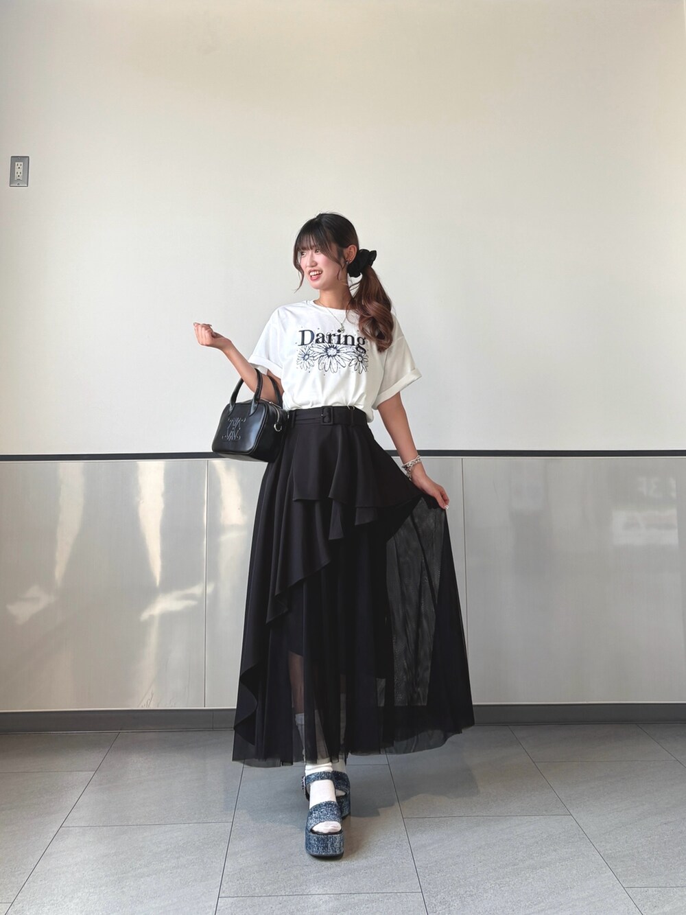 ブラック系のスカート、ホワイト系のTシャツ/カットソー、ブラック系のハンドバッグを着用したレディースの秋コーディネートの2枚目の写真