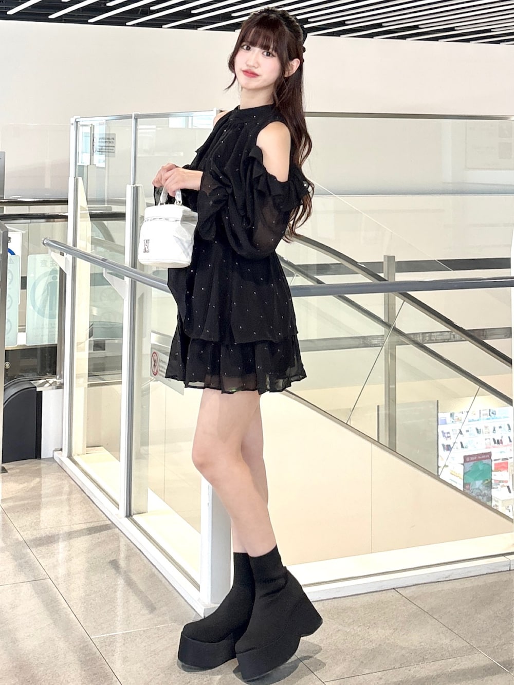 ブラック系のワンピース、ブラック系のブーツ、ホワイト系のショルダーバッグを着用したレディースの秋コーディネートの2枚目の写真
