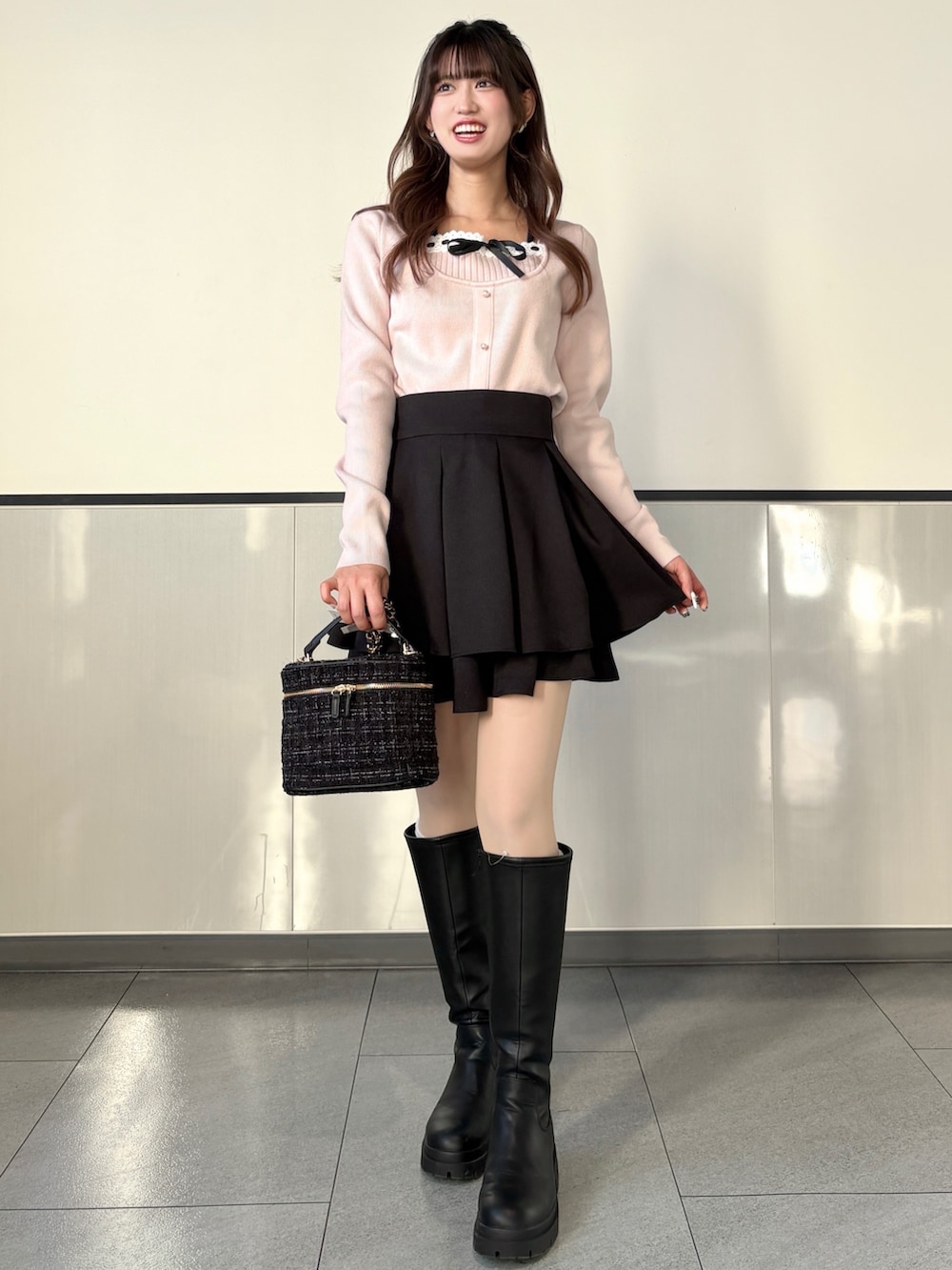 ピンク系のニット/セーター、ブラック系のスカート、ブラック系のブーツを着用したレディースの冬コーディネートの3枚目の写真