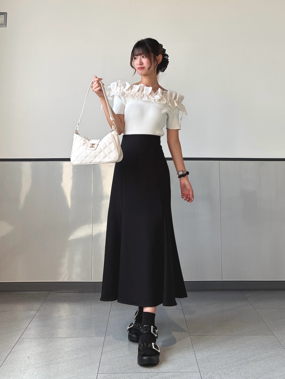 ブラック系のスカート、ホワイト系のショルダーバッグ、ホワイト系のニット/セーターを着用したレディースの秋コーディネートの2枚目の写真
