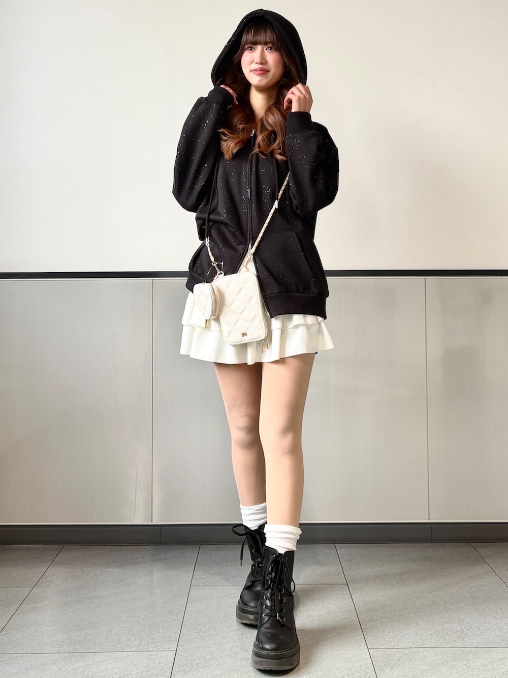 ブラック系のパーカー、ホワイト系のスカートを着用したレディースの冬コーディネートの2枚目の写真