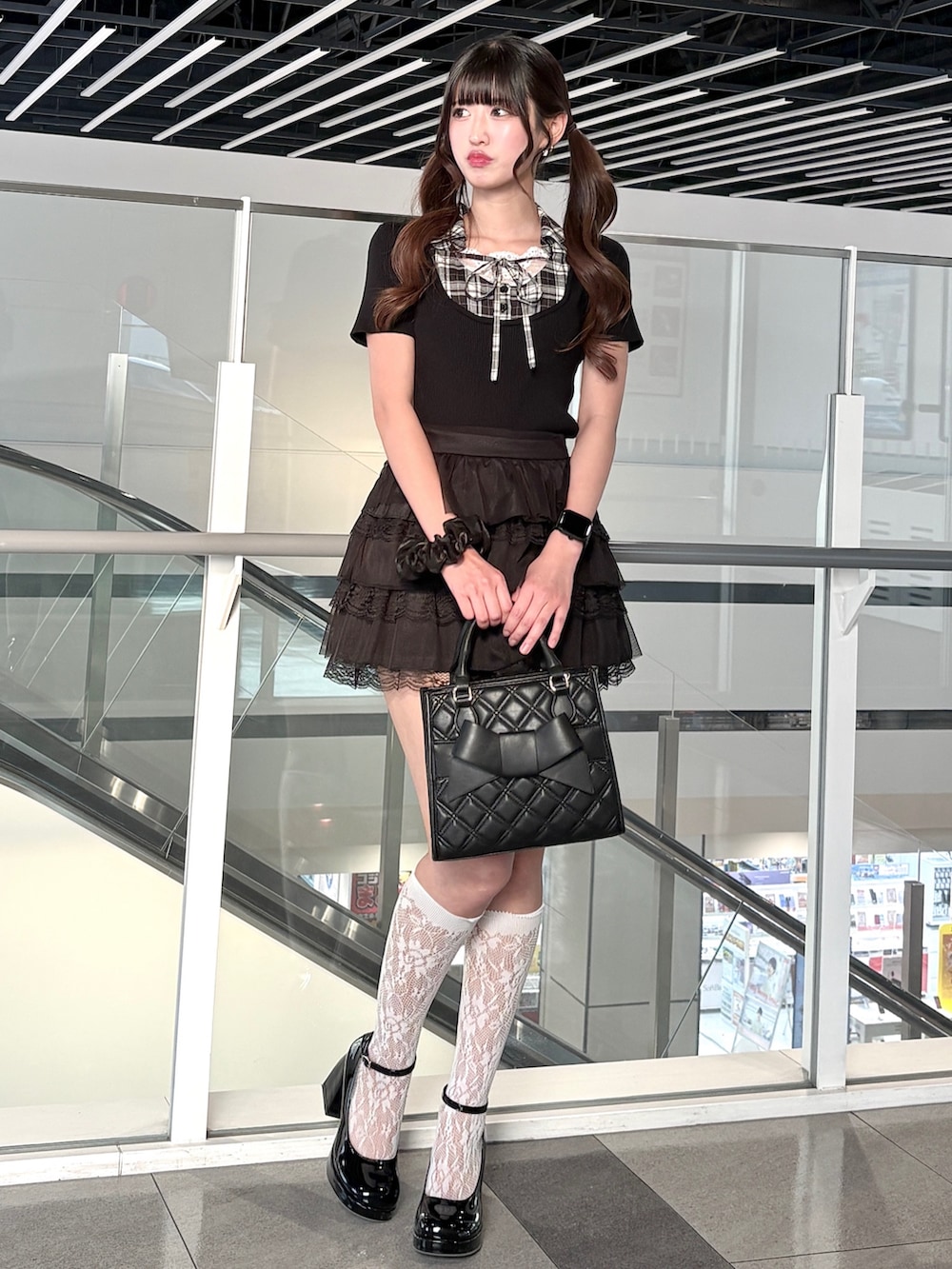 ブラック系のスカート、ブラック系のハンドバッグ、ブラック系のニット/セーターを着用したレディースの春コーディネートの2枚目の写真