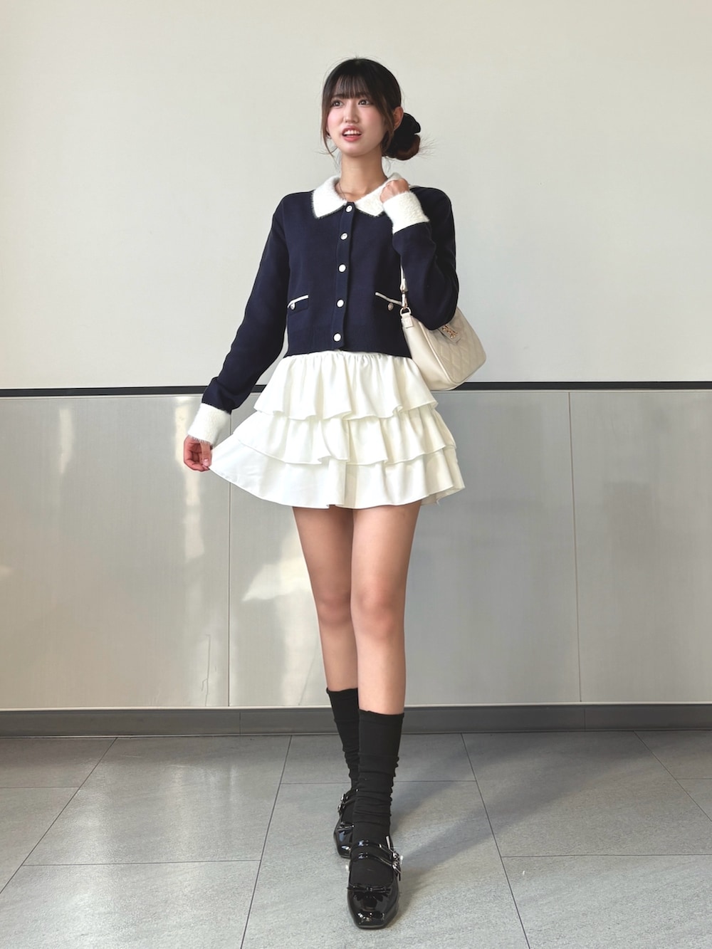 ブルー系のカーディガン/ボレロ、ホワイト系のスカート、ブラック系のパンプスを着用したレディースの秋コーディネートの2枚目の写真