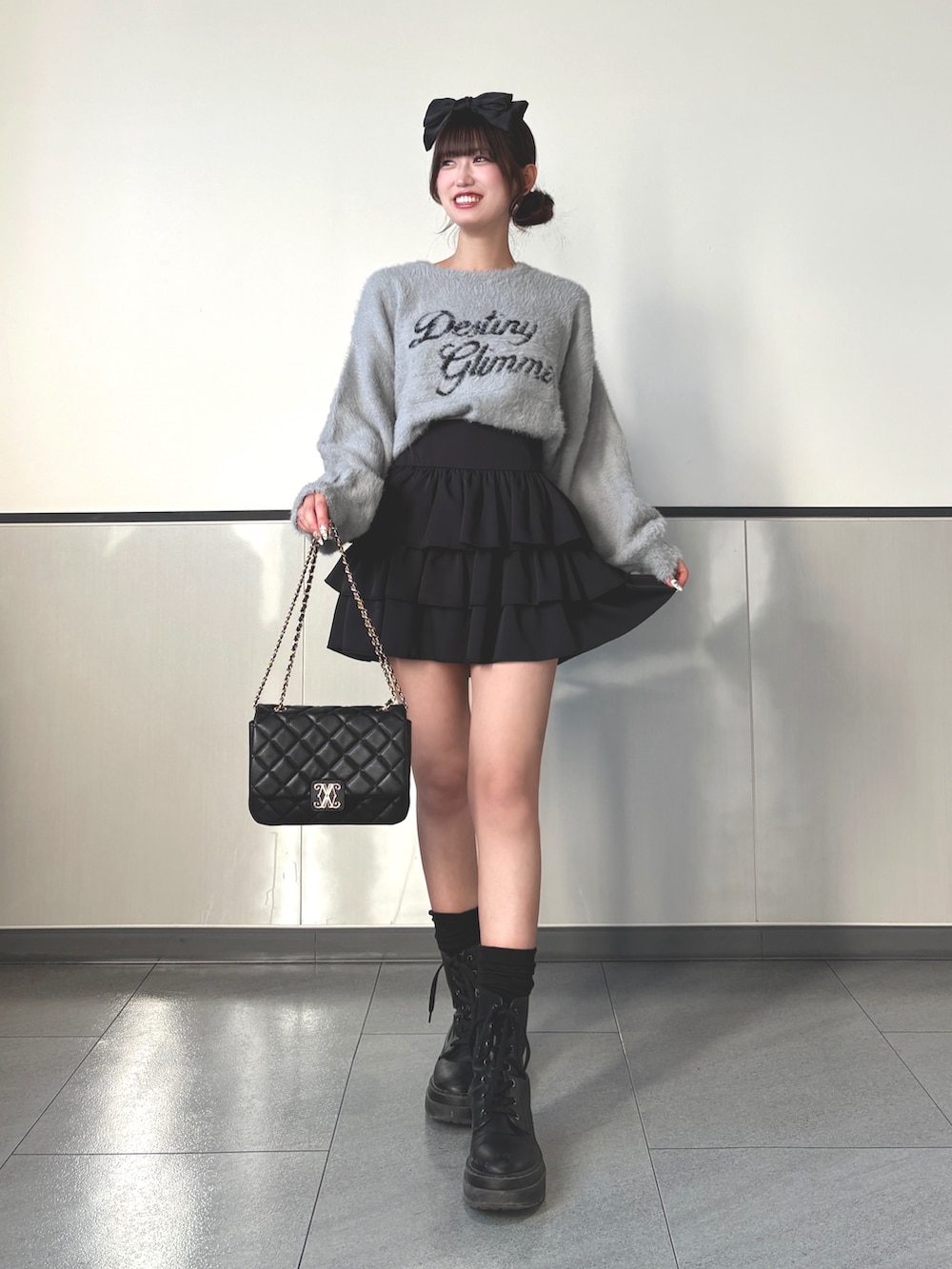グレー系のニット/セーター、ブラック系のスカート、ブラック系のショルダーバッグを着用したレディースの秋コーディネートの2枚目の写真
