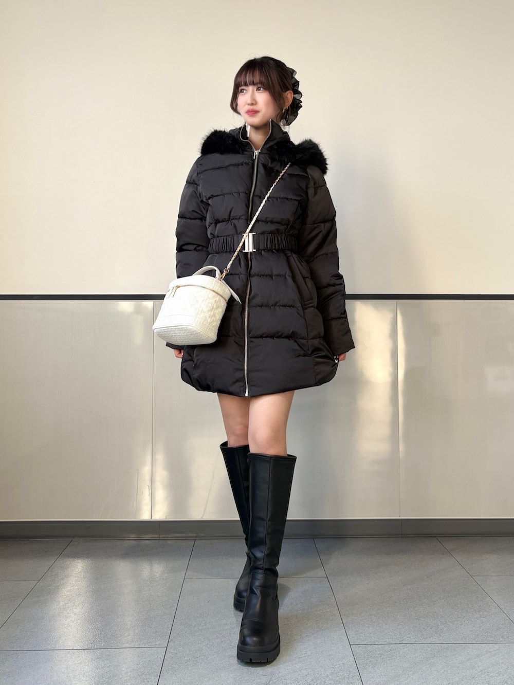ブラック系のダウンジャケット/コート、ホワイト系のショルダーバッグ、ブラック系のブーツを着用したレディースの秋コーディネートの2枚目の写真