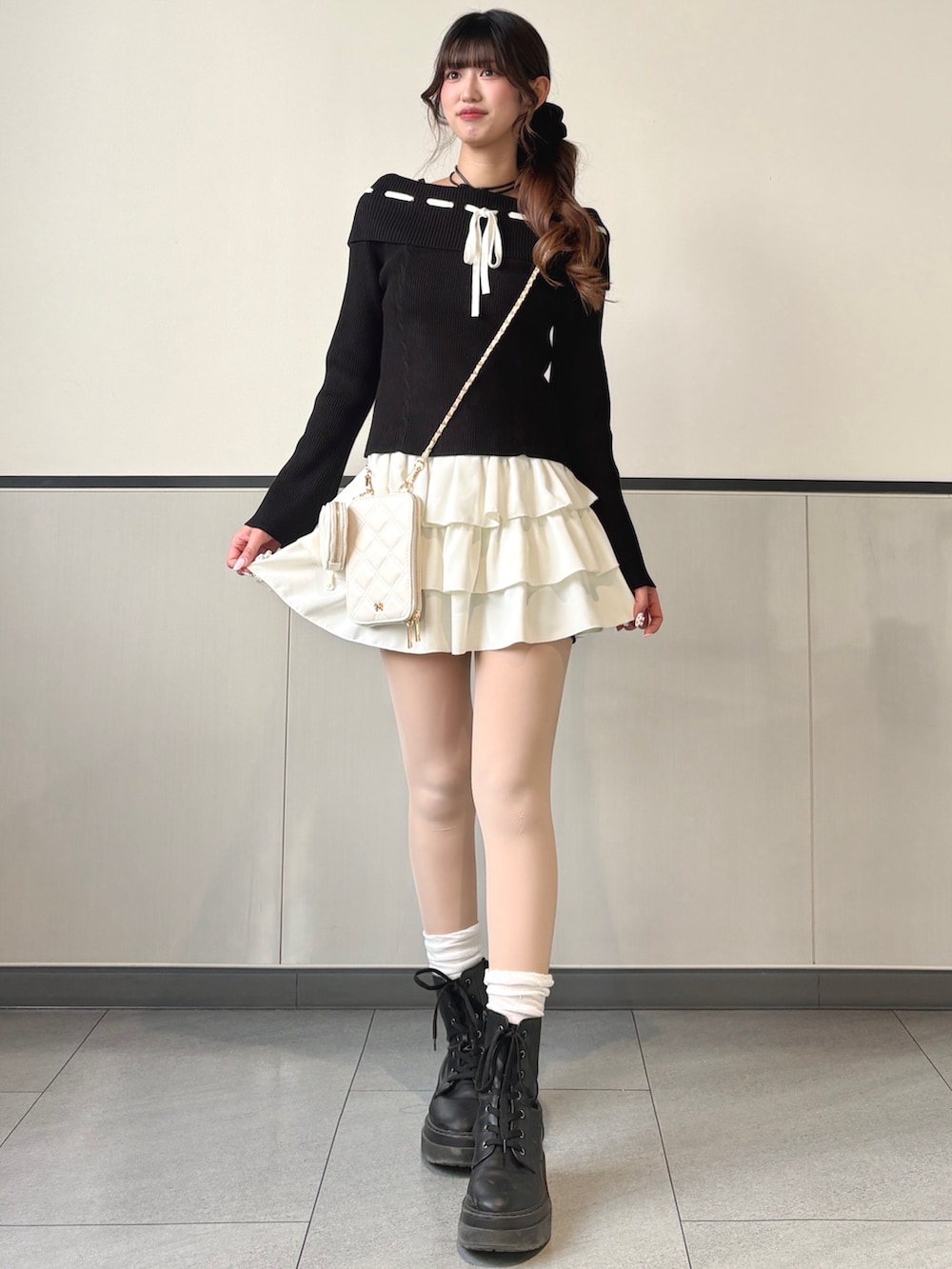 ブラック系のニット/セーター、ホワイト系のスカートを着用したレディースの冬コーディネートの2枚目の写真