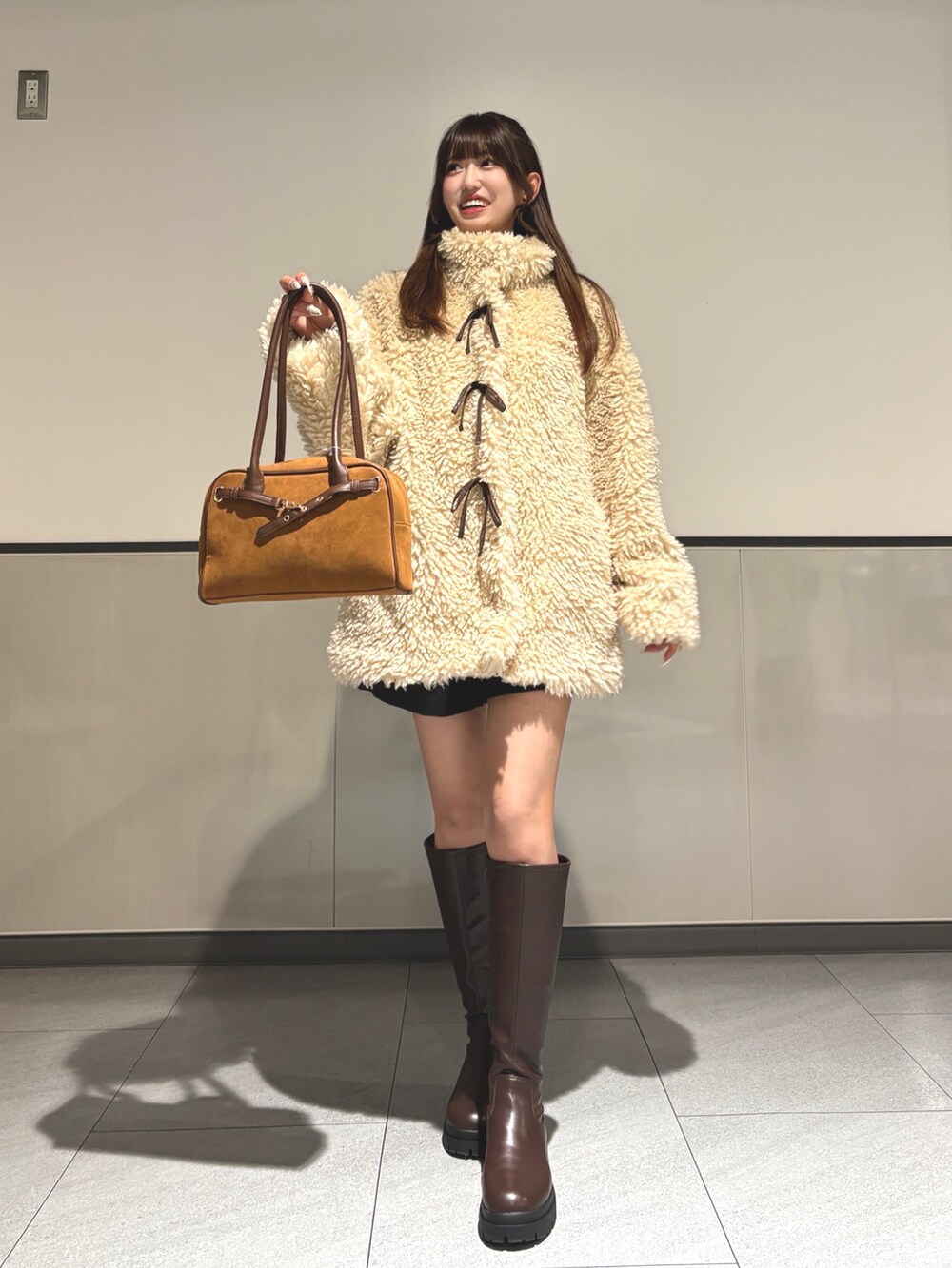 ベージュ系のブルゾン、ブラウン系のブーツ、イエロー系のハンドバッグを着用したレディースの秋コーディネートの2枚目の写真