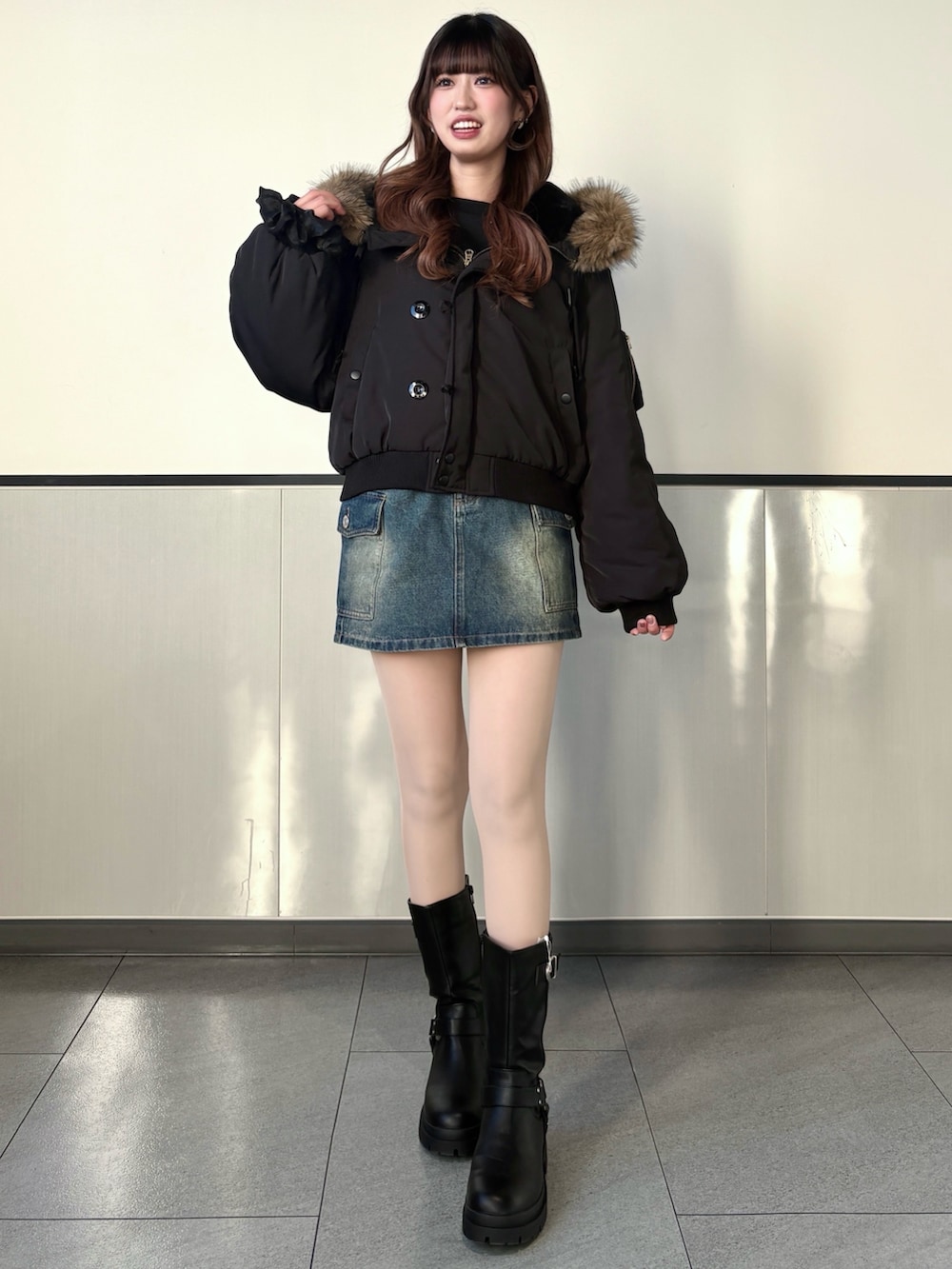 ブラック系のブルゾン、ブルー系のデニムスカート、ブラック系のブーツを着用したレディースの冬コーディネートの3枚目の写真