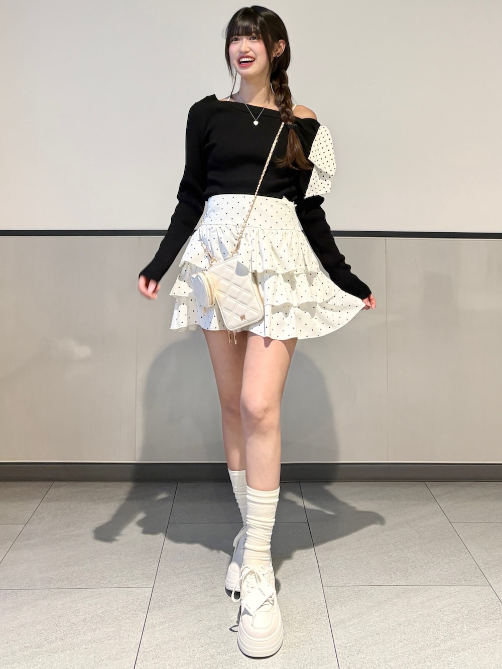 ブラック系のニット/セーター、ホワイト系のスカート、ホワイト系のスニーカーを着用したレディースの春コーディネートの3枚目の写真