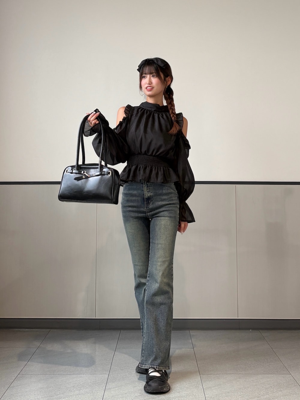 ブラック系のシャツ/ブラウス、ブラック系のハンドバッグ、ブルー系のデニムパンツを着用したレディースの秋コーディネートの2枚目の写真