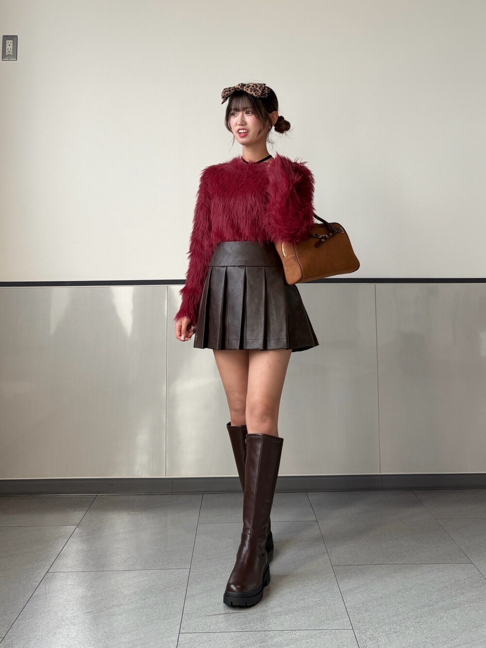 レッド系のニット/セーター、ブラウン系のスカート、ブラウン系のブーツを着用したレディースの秋コーディネートの3枚目の写真