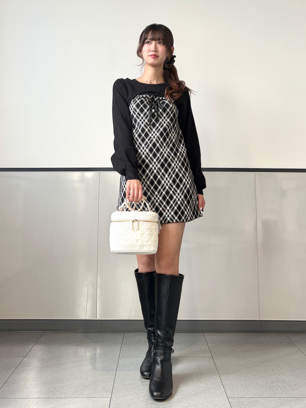 ブラック系のワンピース、ホワイト系のショルダーバッグ、ブラック系のブーツを着用したレディースの秋コーディネートの3枚目の写真