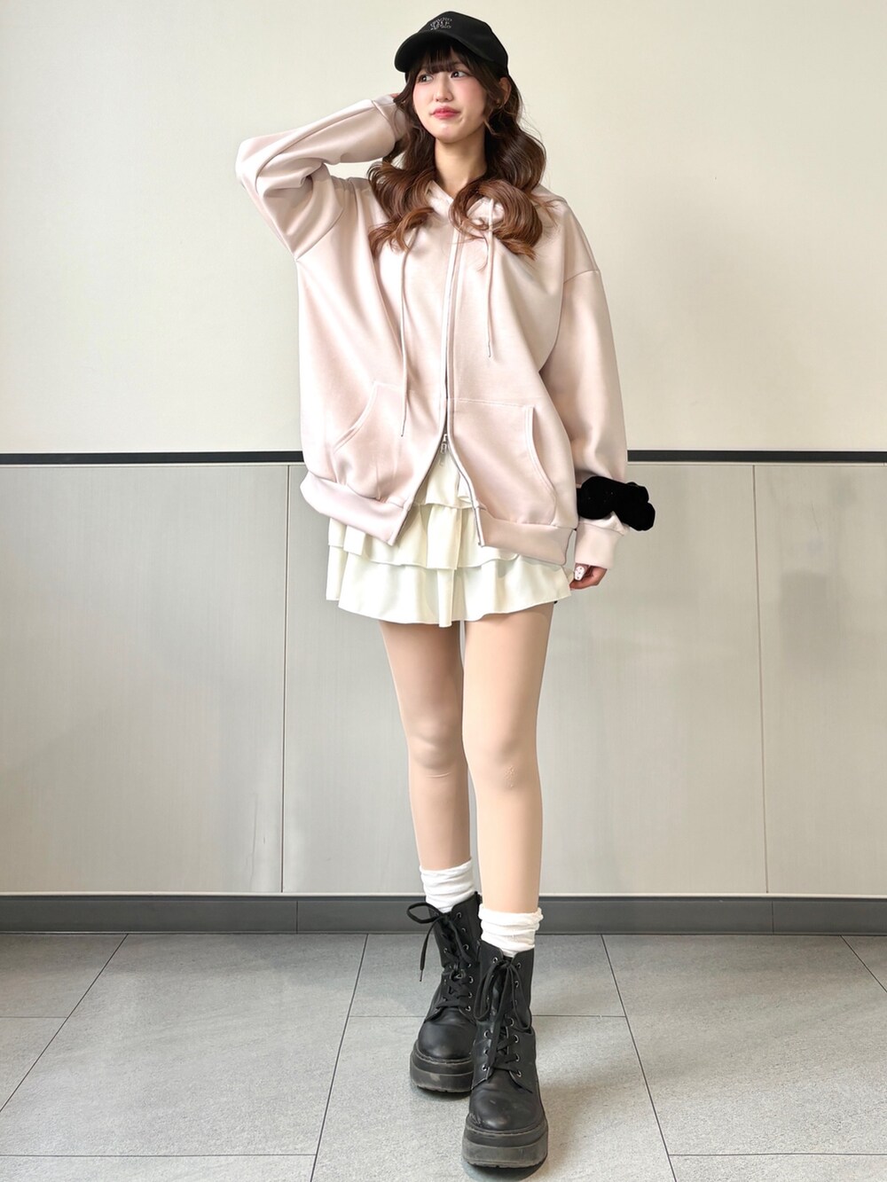 ピンク系のパーカー、ホワイト系のスカート、ブラック系のキャップを着用したレディースの冬コーディネートの3枚目の写真