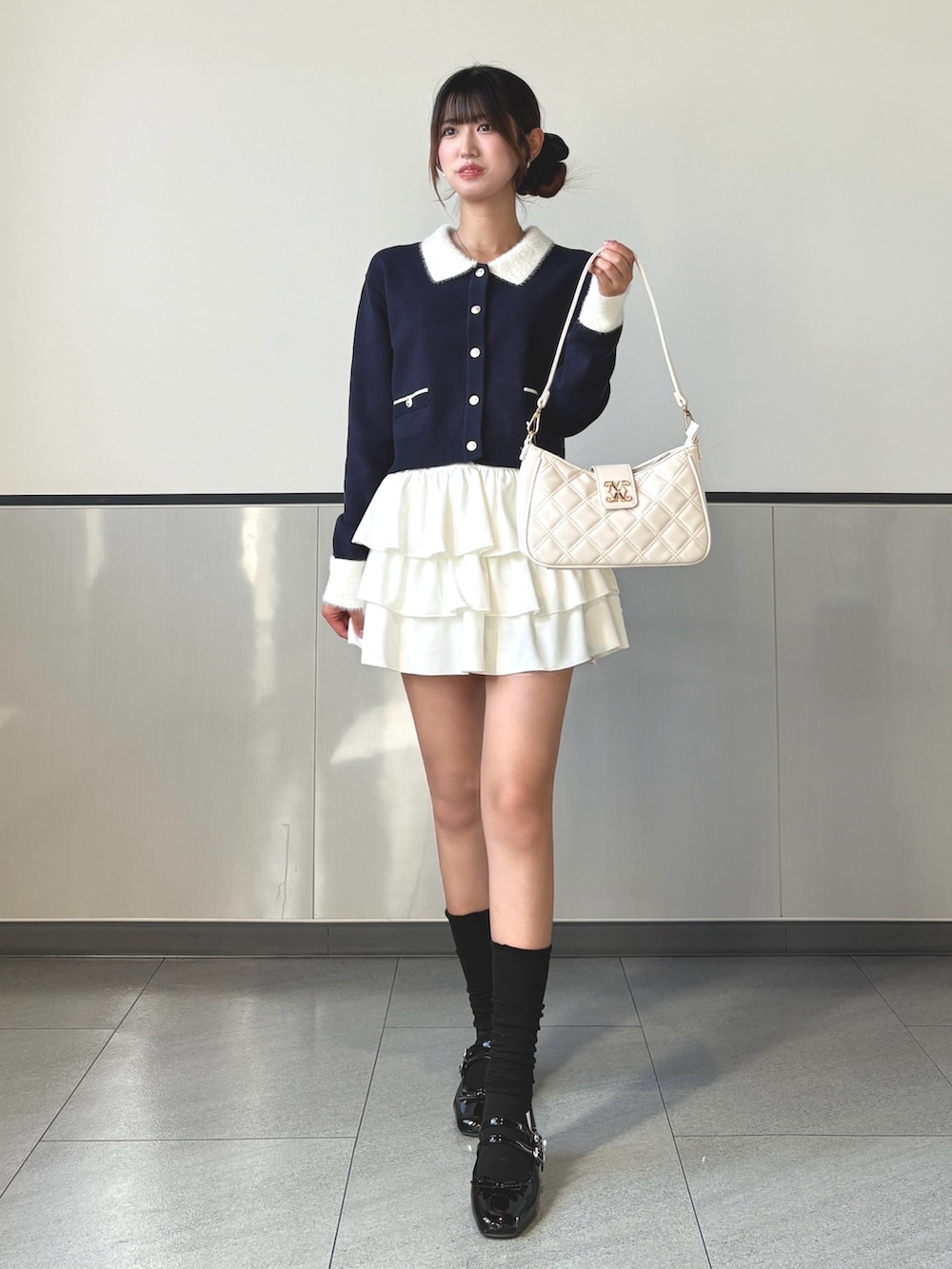 ブルー系のカーディガン/ボレロ、ホワイト系のスカート、ブラック系のパンプスを着用したレディースの秋コーディネートの3枚目の写真