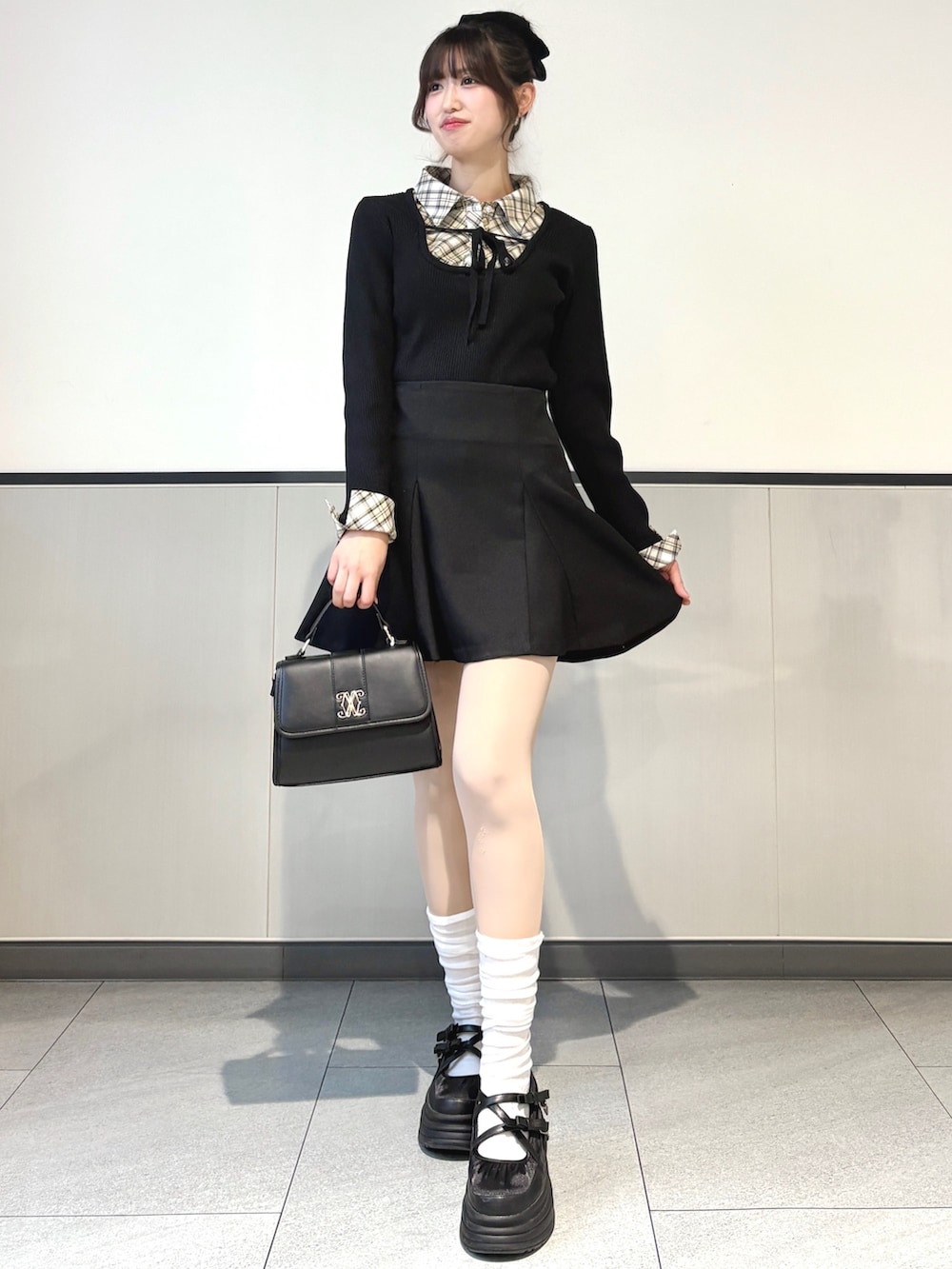 ブラック系のニット/セーター、ブラック系のスカート、ブラック系のハンドバッグを着用したレディースの冬コーディネートの3枚目の写真