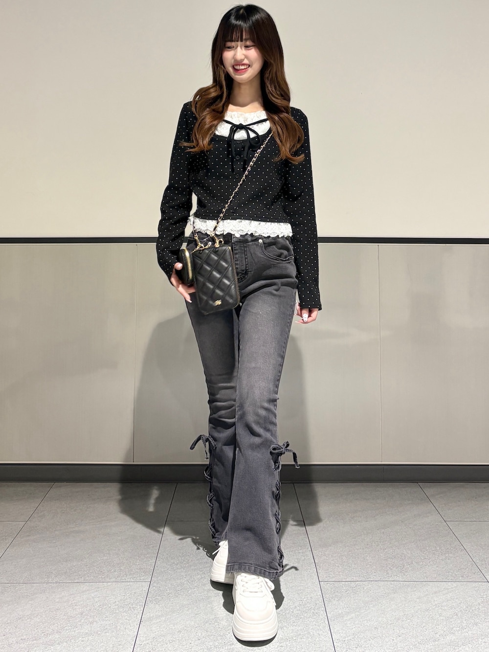 ホワイト系のスニーカー、ブラック系のTシャツ/カットソー、ブラック系のショルダーバッグを着用したレディースの冬コーディネートの2枚目の写真