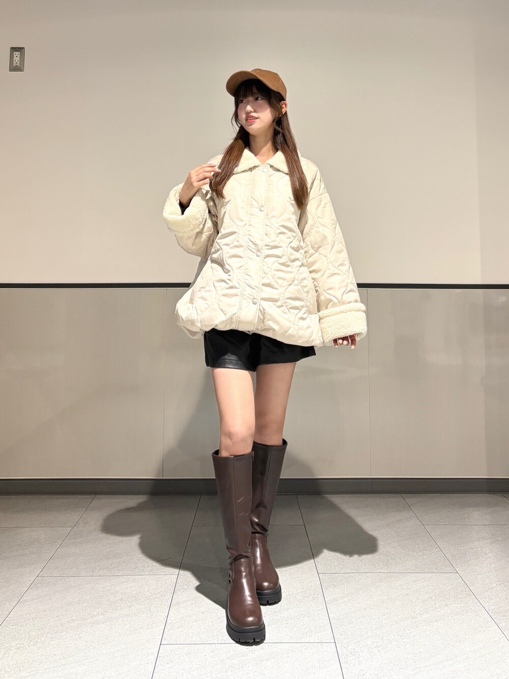 ホワイト系のブルゾン、ブラック系のその他パンツ、ブラウン系のブーツを着用したレディースの秋コーディネートの2枚目の写真