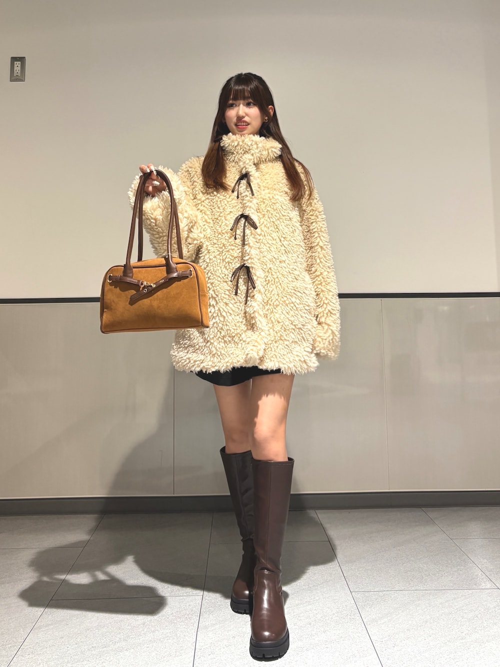 ベージュ系のブルゾン、ブラウン系のブーツ、イエロー系のハンドバッグを着用したレディースの秋コーディネートの3枚目の写真