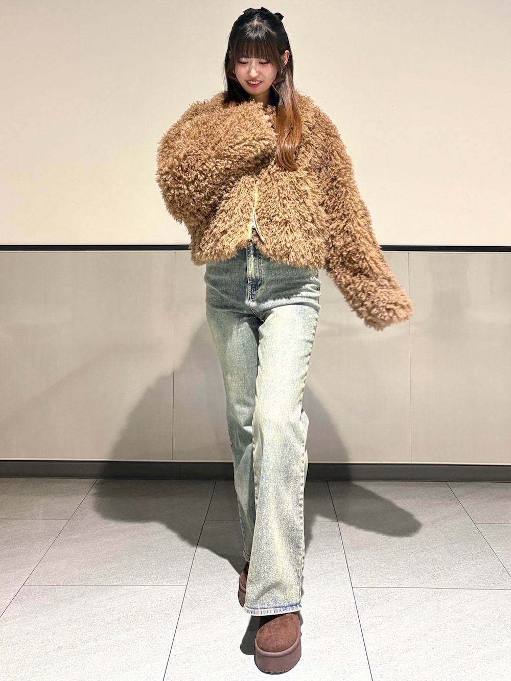 ベージュ系のブルゾン、ブルー系のデニムパンツ、ブラウン系のブーツを着用したレディースの冬コーディネートの2枚目の写真