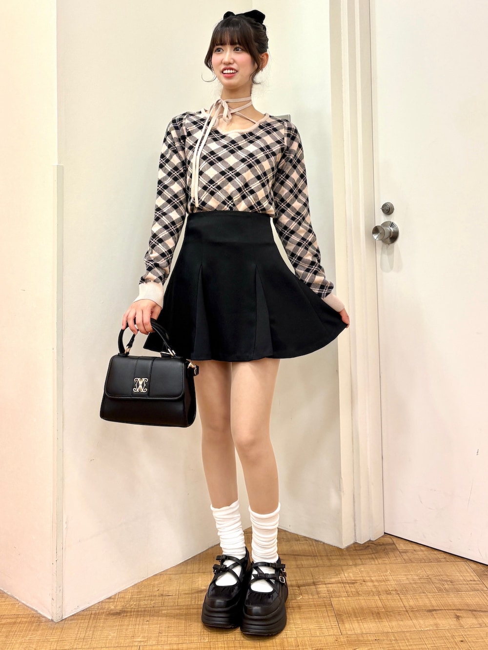 ベージュ系のニット/セーター、ブラック系のスカート、ブラック系のハンドバッグを着用したレディースの冬コーディネートの2枚目の写真