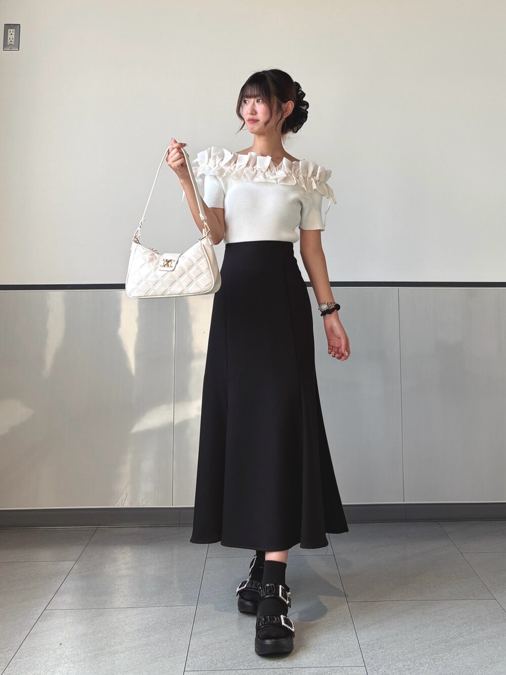 ブラック系のスカート、ホワイト系のショルダーバッグ、ホワイト系のニット/セーターを着用したレディースの秋コーディネートの3枚目の写真