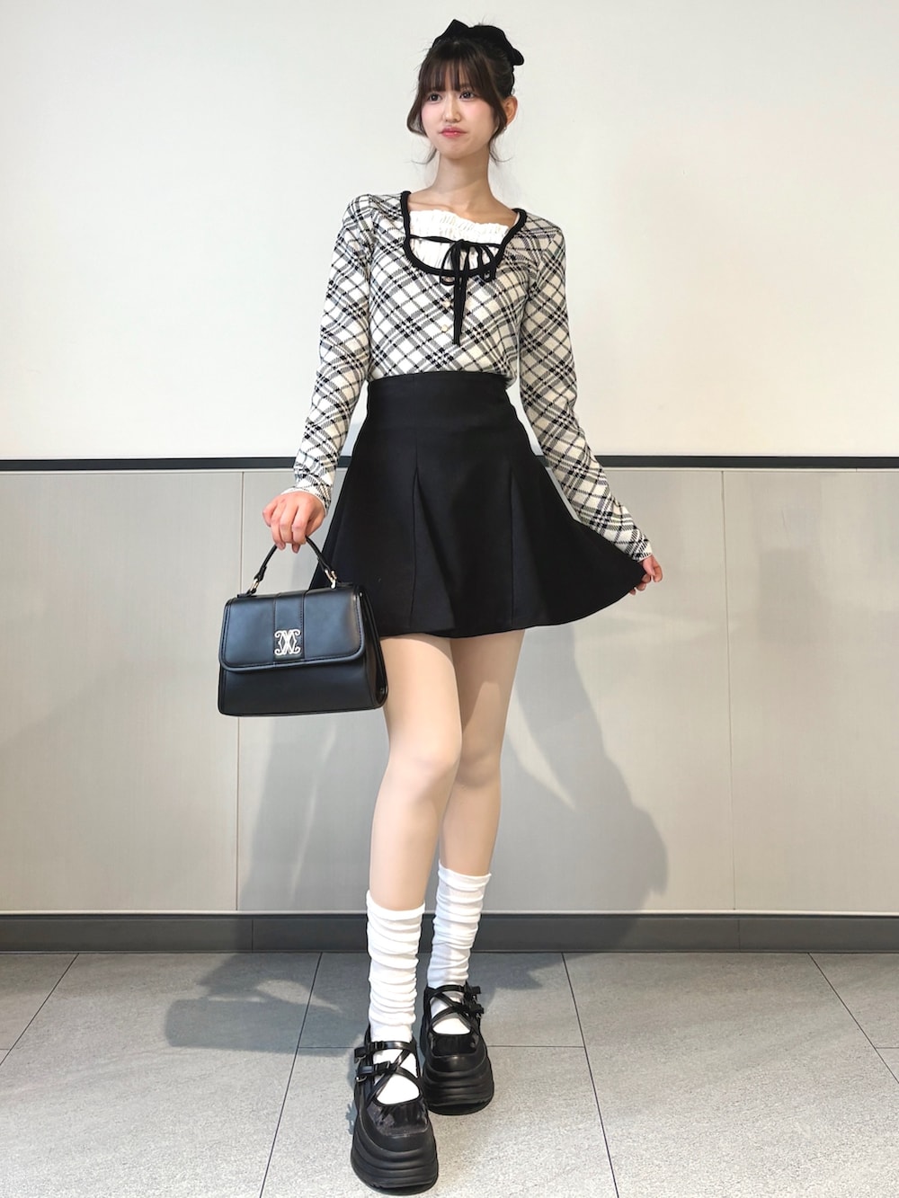 ブラック系のスカート、ブラック系のハンドバッグ、ベージュ系のニット/セーターを着用したレディースの冬コーディネートの2枚目の写真