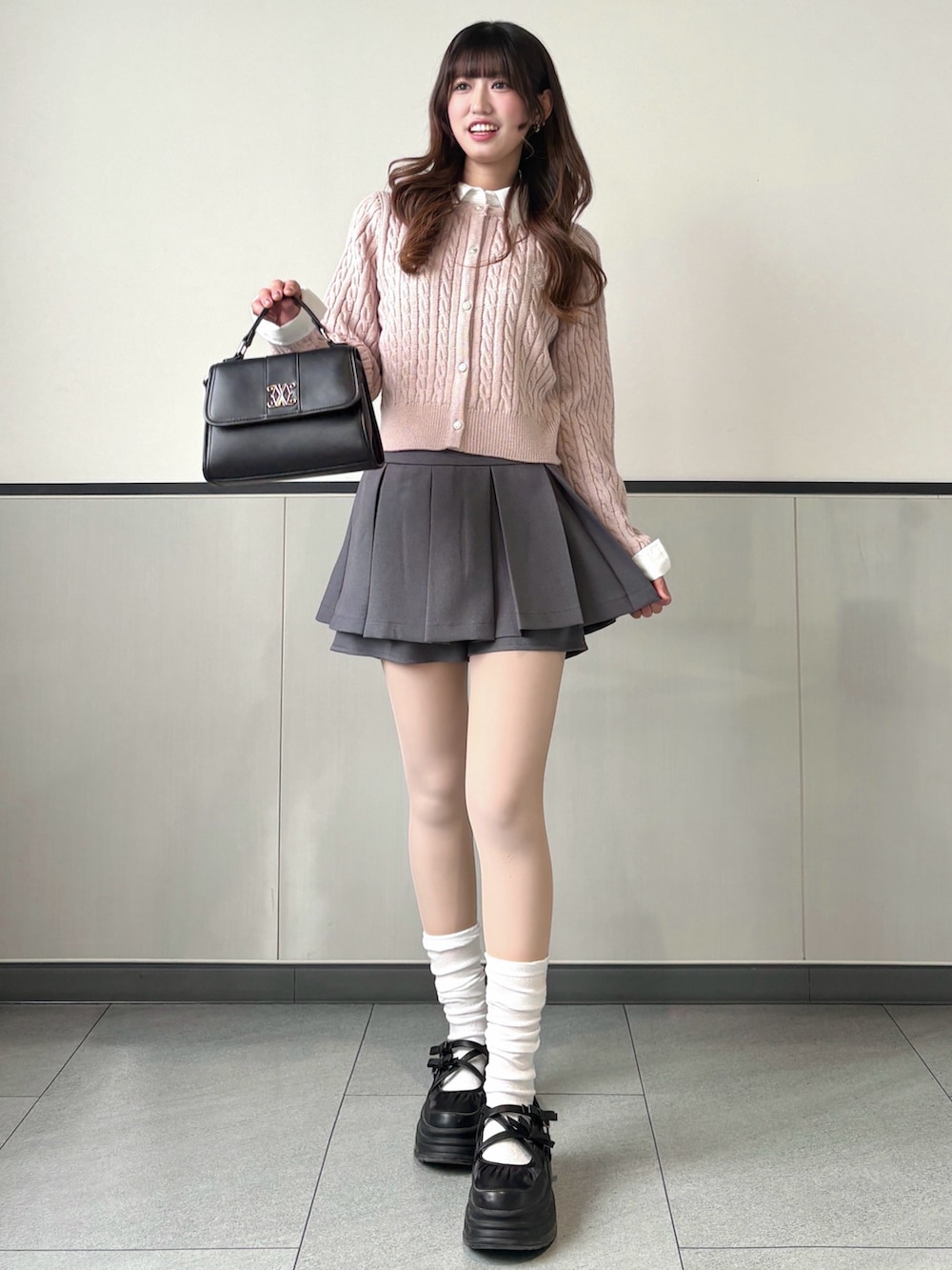 ピンク系のニット/セーター、グレー系のスカート、ブラック系のハンドバッグを着用したレディースの冬コーディネートの2枚目の写真