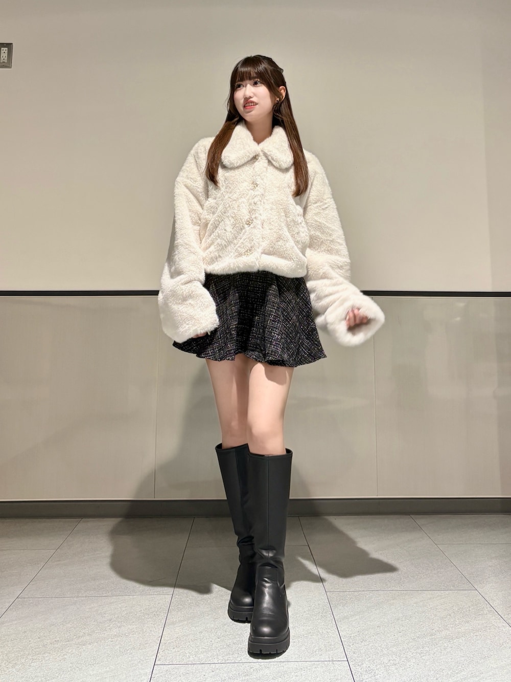 ホワイト系のブルゾン、ブラック系のスカート、ブラック系のブーツを着用したレディースの秋コーディネートの2枚目の写真