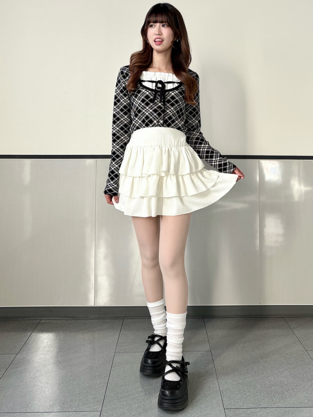 ブラック系のニット/セーター、ホワイト系のスカート、ブラック系のハンドバッグを着用したレディースの冬コーディネートの2枚目の写真