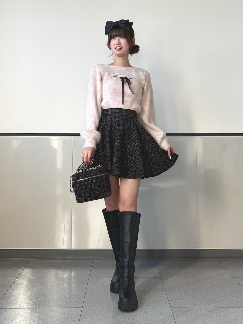 ピンク系のニット/セーター、ブラック系のスカート、ブラック系のブーツを着用したレディースの秋コーディネートの2枚目の写真