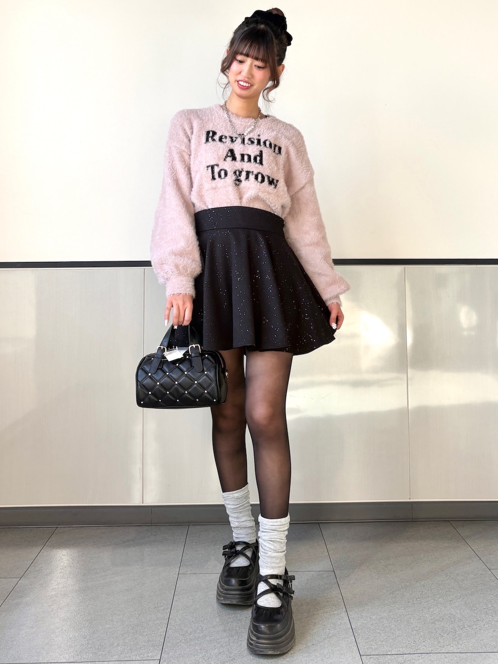 ピンク系のニット/セーター、ブラック系のスカート、ブラック系のボストンバッグを着用したレディースの冬コーディネートの2枚目の写真