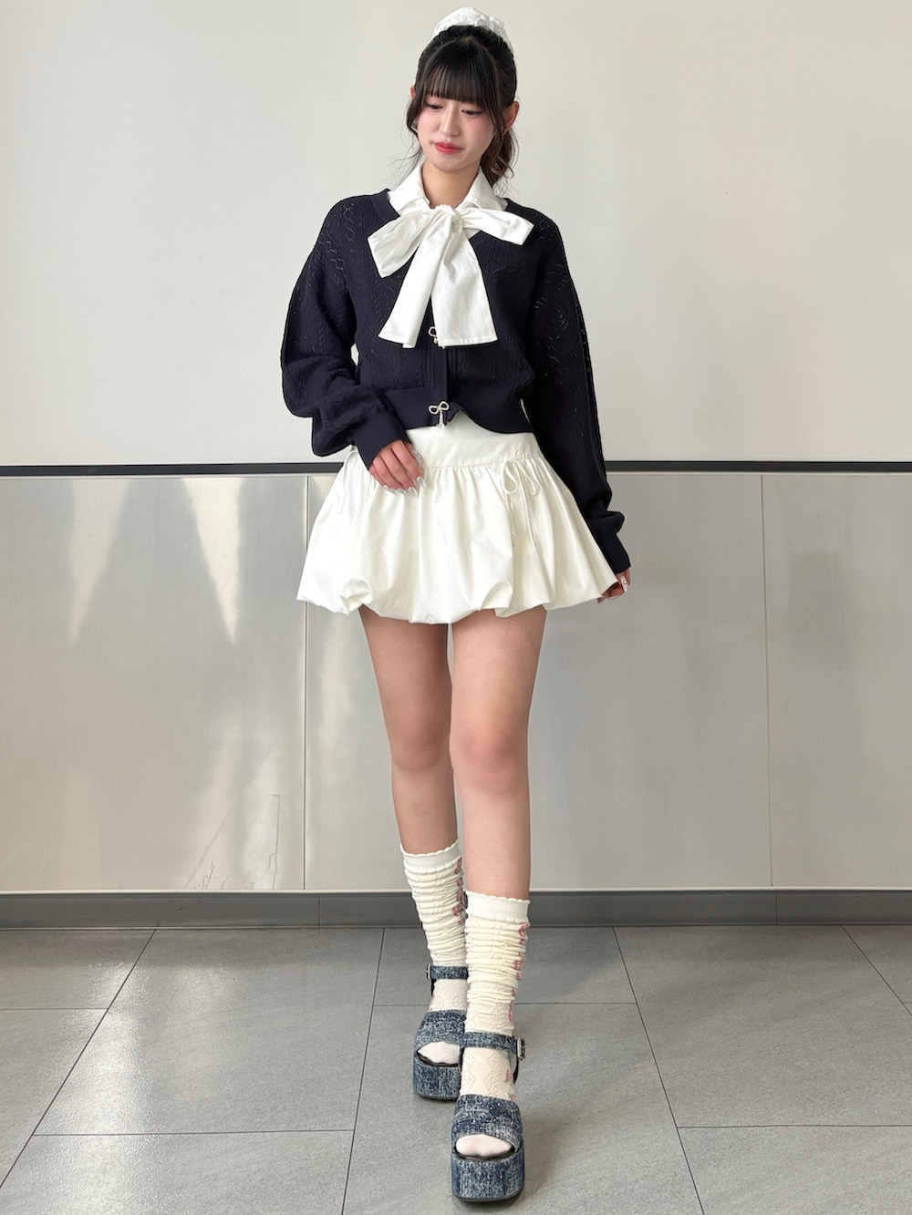 ブルー系のカーディガン/ボレロ、ホワイト系のスカート、ホワイト系のボストンバッグを着用したレディースの春コーディネートの3枚目の写真