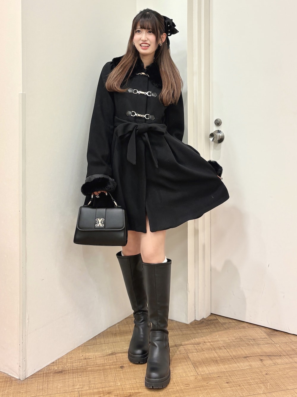 ブラック系のその他アウター、ブラック系のブーツ、ブラック系のハンドバッグを着用したレディースの冬コーディネートの2枚目の写真