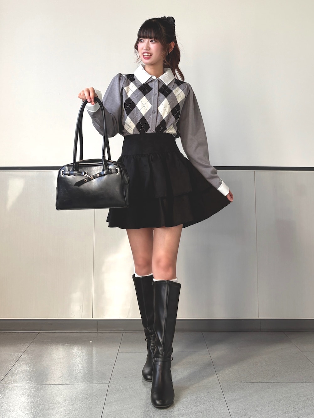 グレー系のニット/セーター、ブラック系のハンドバッグ、ブラック系のスカートを着用したレディースの秋コーディネートの3枚目の写真