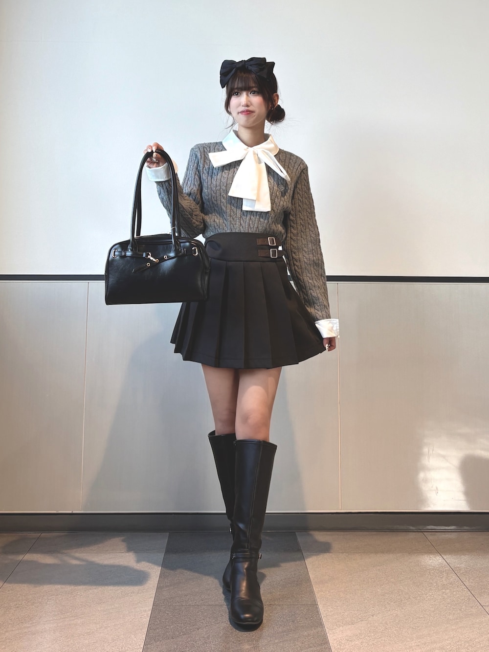 グレー系のニット/セーター、ブラック系のスカート、ブラック系のブーツを着用したレディースの秋コーディネートの3枚目の写真