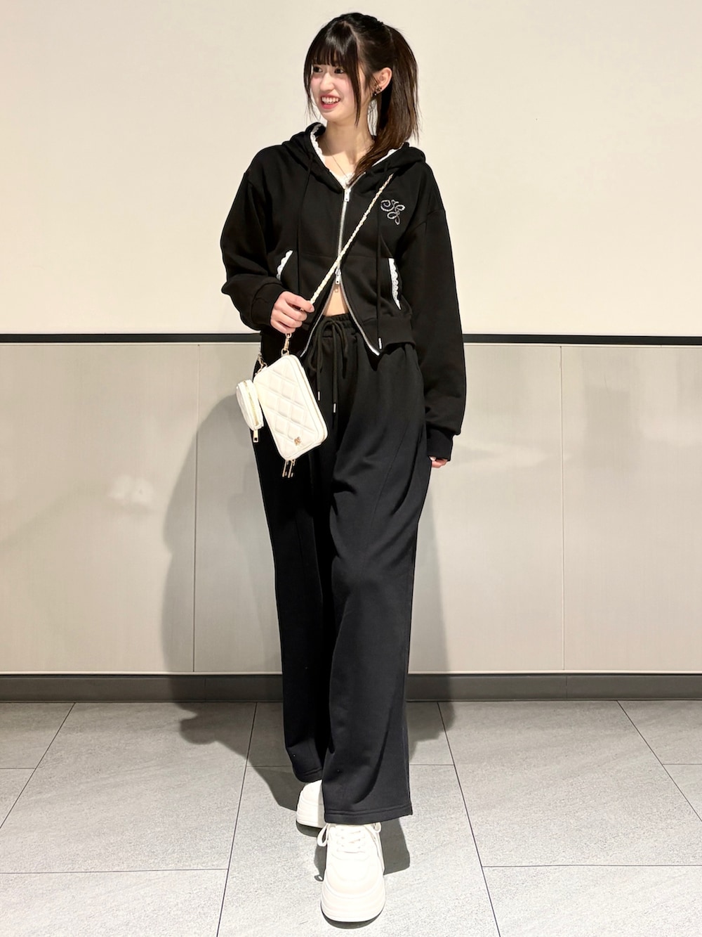 ブラック系のパーカー、ブラック系のスウェットパンツ、ホワイト系のスニーカーを着用したレディースの春コーディネートの2枚目の写真