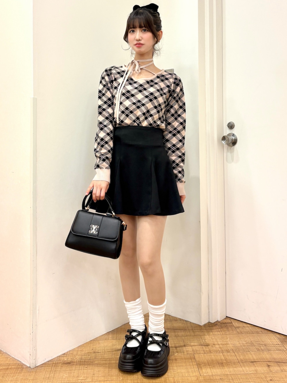 ベージュ系のニット/セーター、ブラック系のスカート、ブラック系のハンドバッグを着用したレディースの冬コーディネートの3枚目の写真