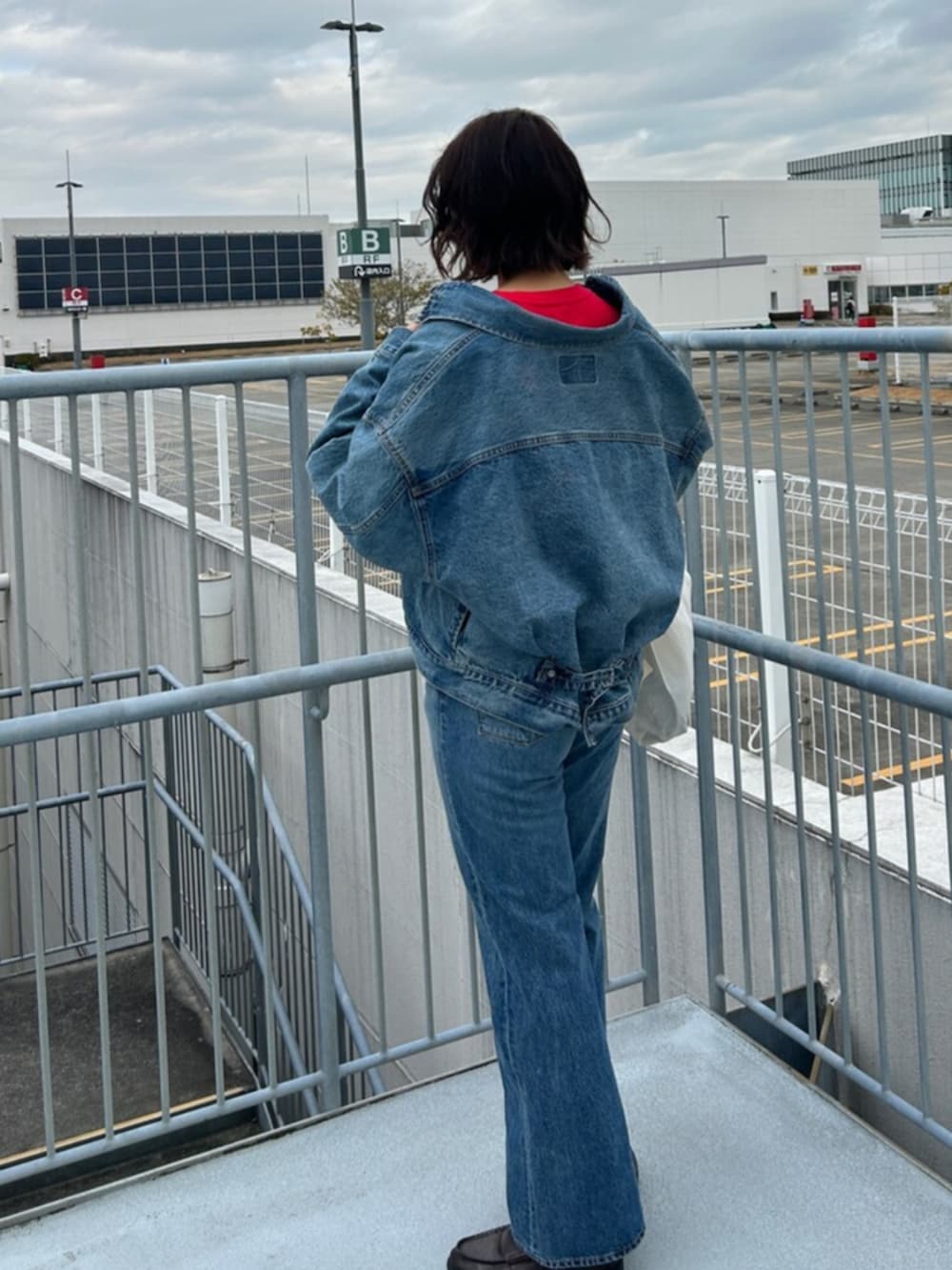 ブルー系のデニムパンツ、ブルー系のデニムジャケット、レッド系のTシャツ/カットソーを着用したレディースの冬コーディネートの3枚目の写真